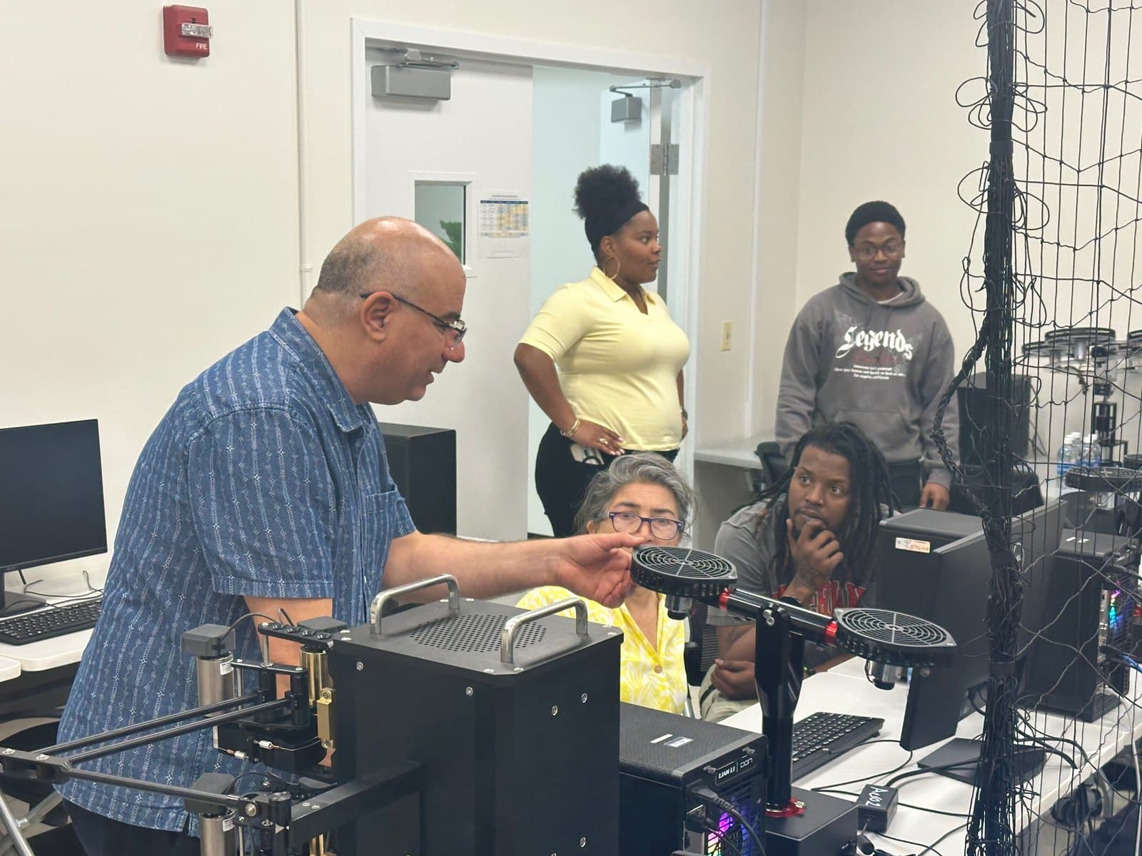 Educators gather around a laboratory equipment demonstration.
