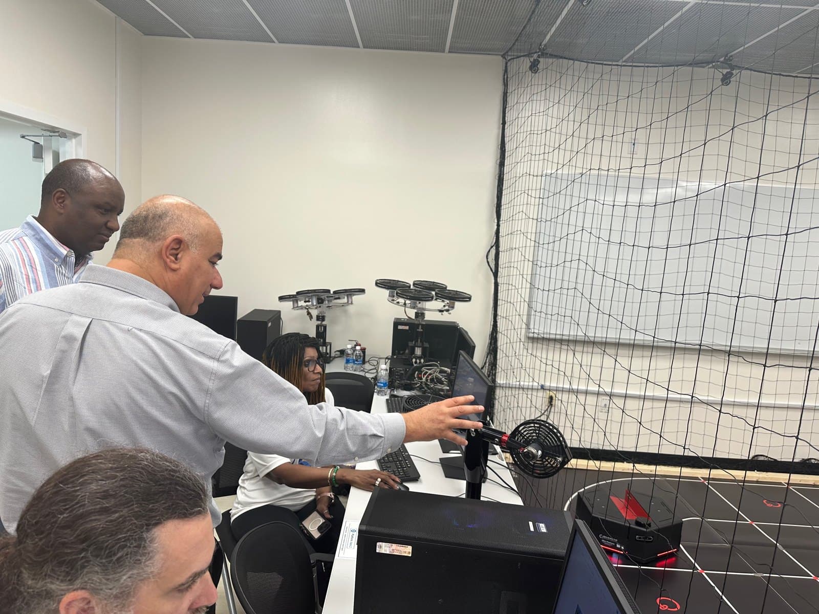 A facilitator points to hardware at a laboratory workstation.